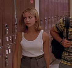 a woman standing in front of lockers with a man behind her looking at the camera