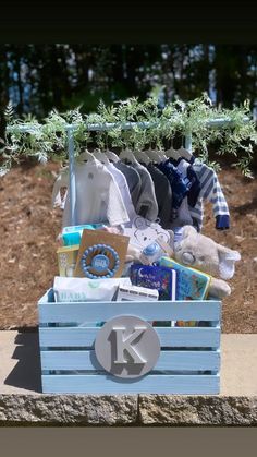 a blue crate filled with baby items sitting on top of a cement slab next to trees