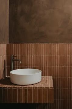 a white bowl sitting on top of a counter next to a faucet sink