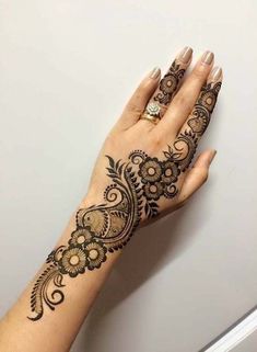 a woman's hand with henna tattoos on her left arm and the wrist