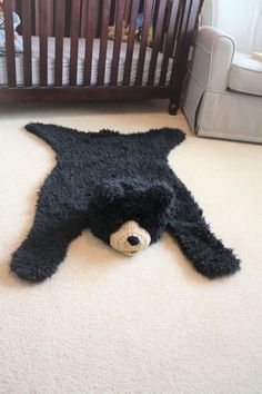 a teddy bear laying on the floor next to a crib