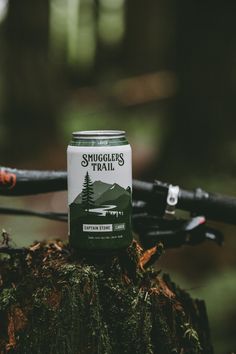 a can of smugler's trail beer sitting on top of a tree stump