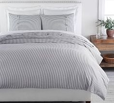 a bed with grey and white comforters in a bedroom