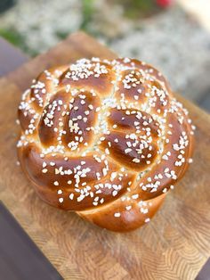 a pretzel sitting on top of a wooden cutting board covered in sesame seeds