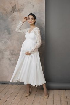 a pregnant woman poses in a white dress