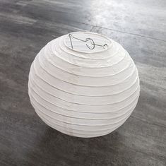 a white paper lantern sitting on top of a wooden floor