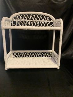 a white wicker shelf with two baskets on it's sides, against a black background