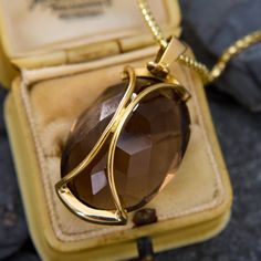 This bold pendant showcases a large oval cut smoky quartz set in a half bezel, with curved bars going down the back of the stone to protect the culet. The pendant is crafted in 14k yellow gold and hangs from a 14k yellow gold, 18 inch rounded box chain finished with a lobster clasp. Elegant Brown Jewelry With Large Stone, Oval Smoky Quartz Jewelry For Gift, Elegant Oval Brown Jewelry, Elegant Brown Oval Jewelry, Elegant Gold Smoky Quartz Necklace, Elegant Yellow Gold Smoky Quartz Jewelry, Curved Bars, Antique Engagement Rings Sapphire, Estate Jewelry Rings