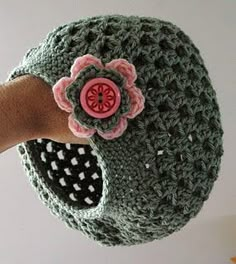 a hand is holding a crocheted hat with a flower on it