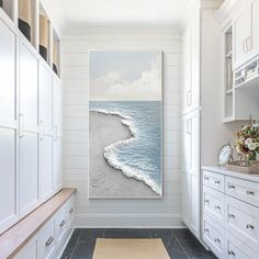 a painting hanging on the wall in a white room next to a rug and cabinets