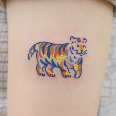 a colorful tiger tattoo on the back of a woman's left arm and leg