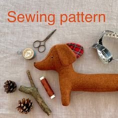 the sewing pattern is on display with scissors, needles and a dog figurine