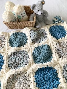 a crocheted blanket with a teddy bear next to it