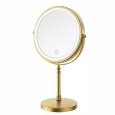 a gold metal stand with a round mirror on it's top and the light is turned on