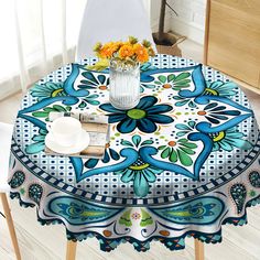 a blue and white table cloth with flowers on it next to a vase filled with orange flowers