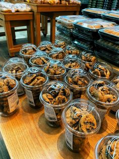 many plastic containers filled with cookies on top of a wooden table next to other food items