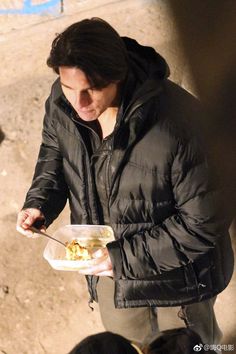 a man in a black jacket is eating food