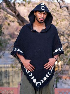 "\"Stay cozy and stylish with the Amavasi Poncho. Made from soft and durable cotton, and featuring a unique blockprint border depicting the phases of the moon, this poncho is perfect for adding a touch of boho to any outfit. Don't forget the convenient hoodie for those chilly nights. Bring on the moon magic!\"" Casual Hooded Poncho For Festival, Casual Winter Cape For Festivals, Oversized Long Sleeve Hippie Poncho, Casual Winter Festival Cape, Oversized Hooded Cotton Poncho, Bohemian Black Hooded Hoodie, Black Bohemian Hoodie, Black Long Sleeve Cotton Poncho, Hooded Cotton Poncho For Festival