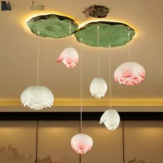 a group of lights hanging from the ceiling above water lilies and lily pad leaves