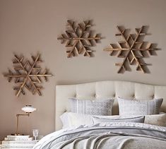 two snowflakes are mounted on the wall above a bed with pillows and blankets