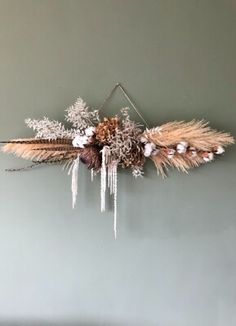 an arrangement of dried flowers hanging on the wall with icicles attached to it's sides