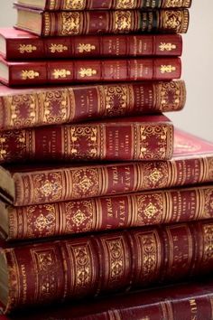 a stack of red books sitting on top of each other next to a white wall