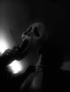 a person in a dark room with a light on their head and a mask hanging from the ceiling