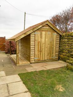 a wooden shed sitting next to a stone wall