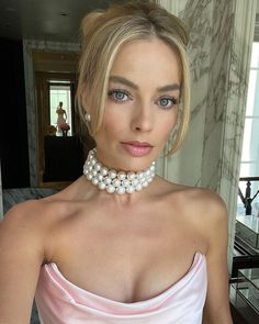 a woman in a pink dress wearing a pearl choker and pearls on her neck