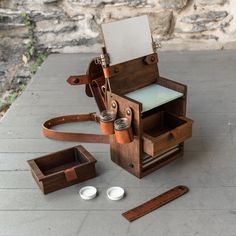 an old fashioned wooden box sitting on top of a table next to two empty cups