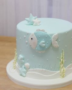 a blue and white cake with fish on it sitting on a table next to a wall