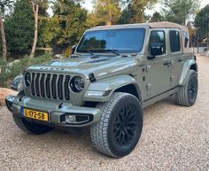 a grey jeep is parked in the gravel