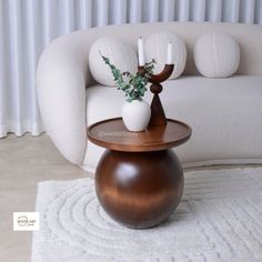 a wooden table with a vase on it sitting in front of a white couch and rug