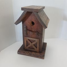 a wooden birdhouse with a door and window on it's side sitting on a white surface