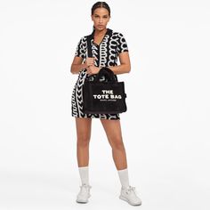 A luxurious style that accommodates all your everyday necessities, The Medium Tote by Marc Jacobs is crafted from black terry, adorned with the brand's unique lettering on the front in a striking white contrast. Providing a variety of styling possibilities, the bag features both top handles and a cross-body strap for convenience..Black and white terry.Detachable shoulder strap, top handles, designer patch.Internal zipped pocket, two slip pockets, card slot.Zip closure.Dimensions: H: 27cm x W: 34 Casual Black Bags With Logo Print, Trendy Black Bags With Logo Print, Unique Lettering, Tan Bag, Branding Coach, Beige Bag, Buy Bags, Small Tote Bag, The Medium