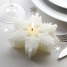 a candle that is on top of a table with silverware and snowflakes