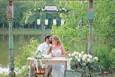 a bride and groom sitting at an outdoor table