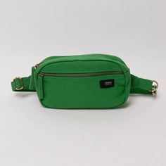 The Cadera Fanny Pack is the perfect size—wear it on your hip or as a tiny sling bag. This eco-friendly fanny pack, made with organic cotton canvas, lets you move through your day hands-free. The main zippered compartment features a simple drop-in pocket to keep phone screens separate from scratchy items like keys. An external zippered pocket secures other small items and keeps them handy. The adjustable strap with a snap hook makes it easy to get on and off. Additionally, your purchase supports Feeding America, Lavender Green, Cotton Bag, Sling Bag, Hands Free, Fanny Pack, Plastic Bag, The Journey, Front Zipper