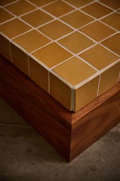 a close up of a wooden box with tile on it's sides and wood in the middle