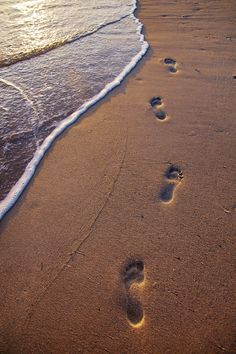 two footprints in the sand next to the ocean