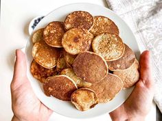 a person holding a plate with pancakes on it