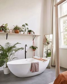 a bathtub in the middle of a room with potted plants