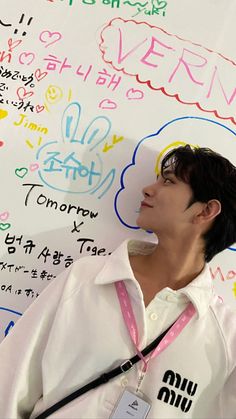 a young man standing in front of a white board with writing on it's side