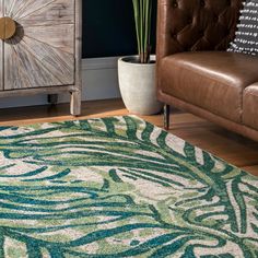 a green and white rug in a living room next to a brown leather chair with a potted plant