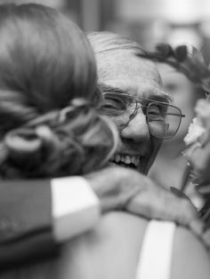 an old man and woman hugging each other at a table with flowers in their hair