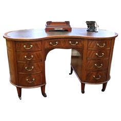 an antique wooden desk with drawers and a clock on top