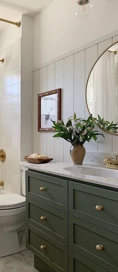 a white toilet sitting next to a bath tub in a bathroom under a mirror above a sink