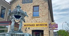 a large metal fountain in front of a brick building with a sign for the museum