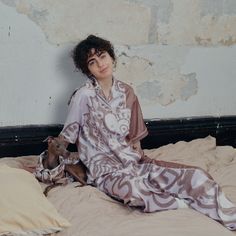 a woman sitting on top of a bed next to a pillow and stuffed animal toy