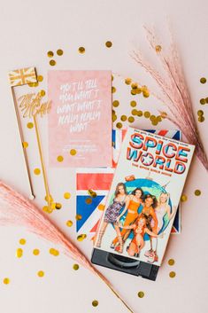 some books and gold confetti on a white table with pink and blue decorations